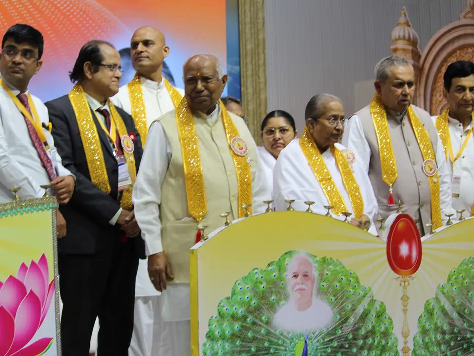 A row of guests wearing ceremonial shawls standing on stage