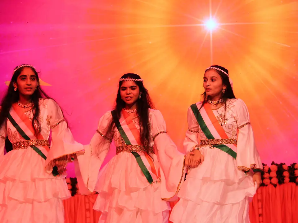 Two dancers in white with tricolour sashes performing on stage