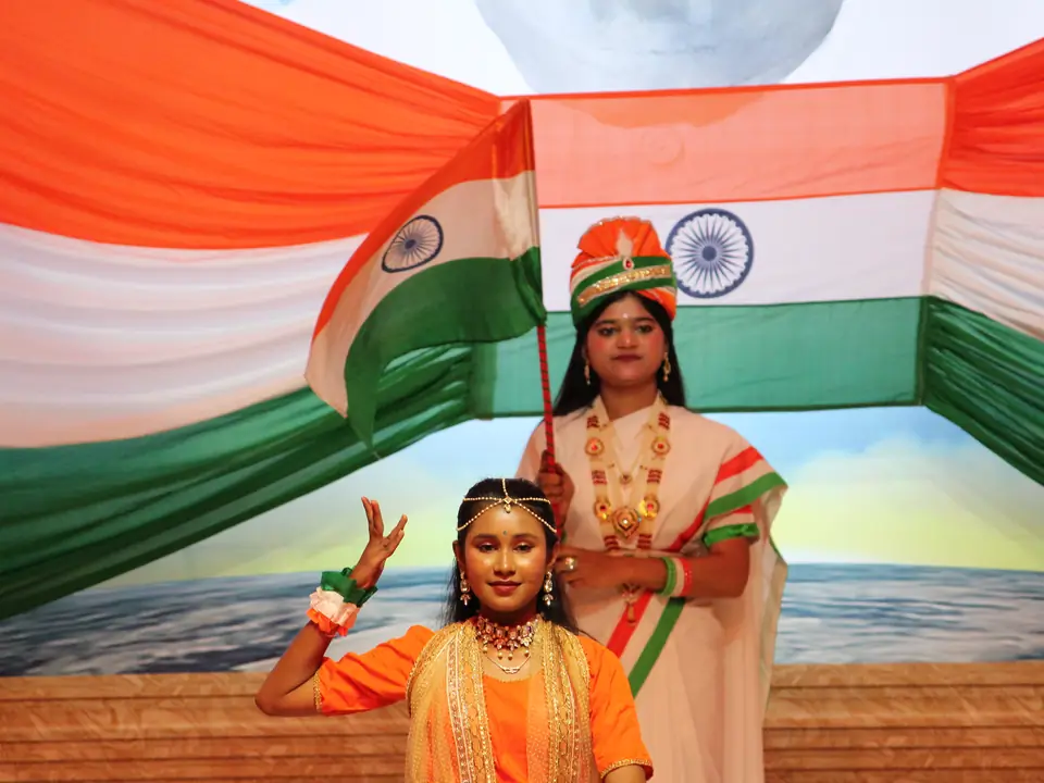 A performer before a large tricolour backdrop on stage