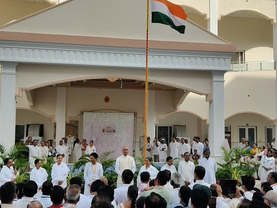 A gathering standing before the flagpole at the campus